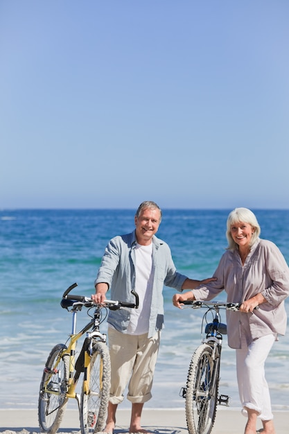 Coppia di anziani con le loro biciclette sulla spiaggia