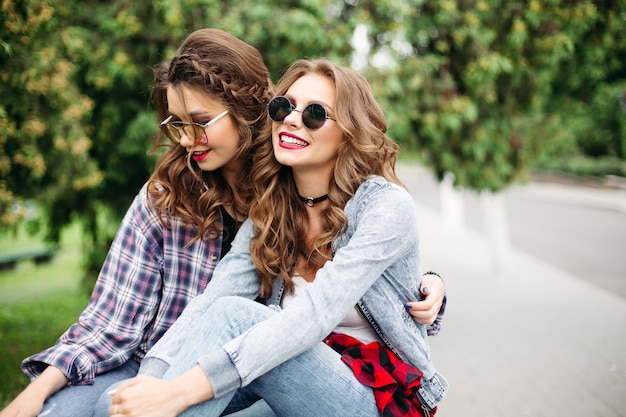 Coppia di belle ragazze adolescenti alla moda in occhiali da sole nel parco.