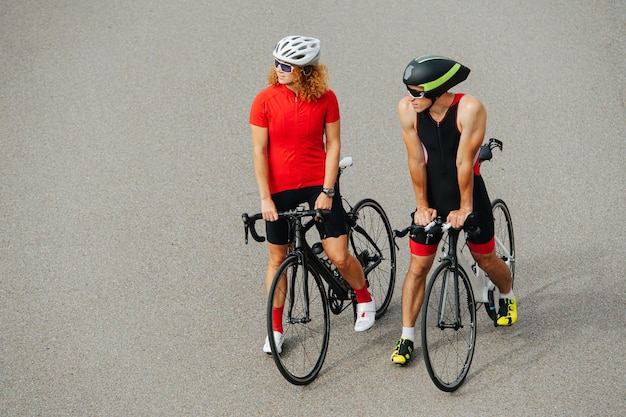 Coppia di ciclisti in piedi su un pavimento di cemento con le biciclette tra le gambe