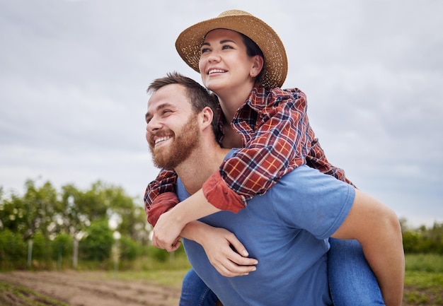 Coppia di coltivatori agricoli giocosi che si divertono in una fattoria, campagna o ambiente naturale, godendo di uno stile di vita rustico e sostenibile Felice premuroso e innamorato marito che dà alla moglie un giro sulle spalle