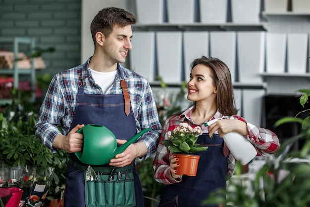 Coppia di giardinieri, ragazza e uomo con piante nel bellissimo centro giardino o centro botanico