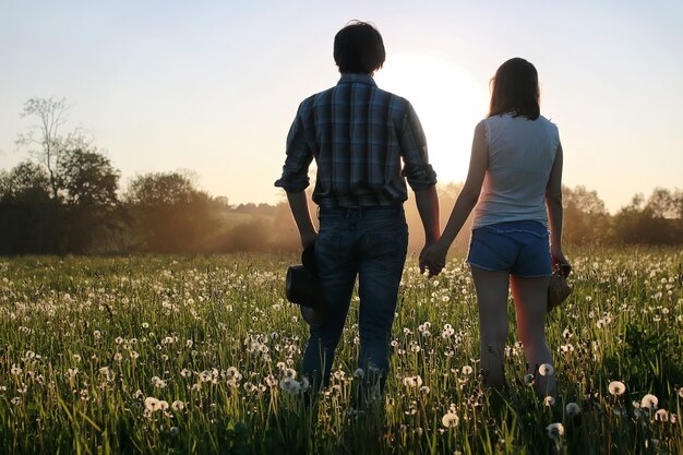 Coppia di giovani che camminano nel tramonto della sera primaverile in campo