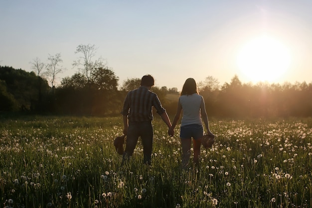 Coppia di giovani che camminano nel tramonto serale primaverile in campo