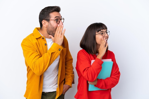 Coppia di giovani studenti isolati su sfondo bianco che gridano con la bocca spalancata lateralmente