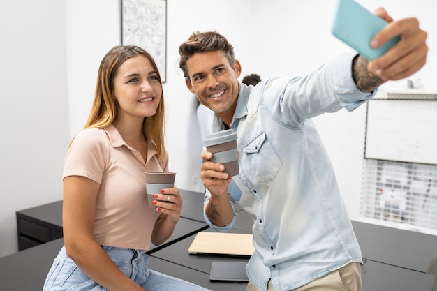 Coppia di impiegati si fanno un selfie mentre bevono un caffè