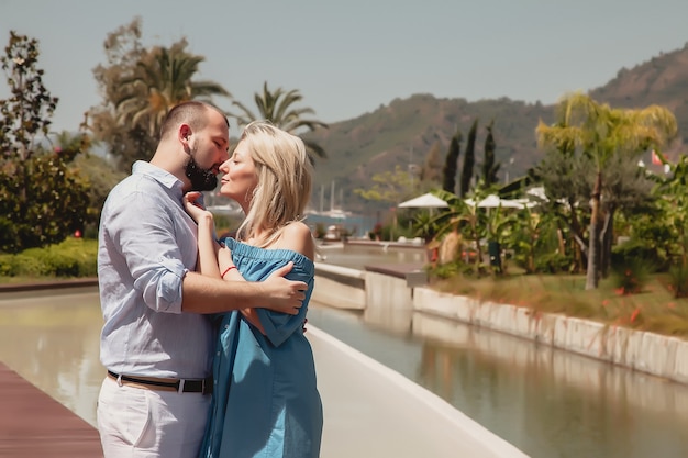 Coppia di innamorati che si godono la luna di miele in un hotel di lusso, passeggiando per giardini con palme e piscina