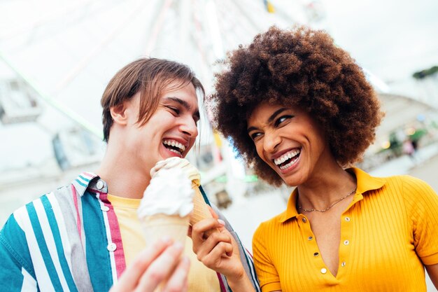 Coppia di innamorati che si incontrano al parco divertimenti e mangiano gelati