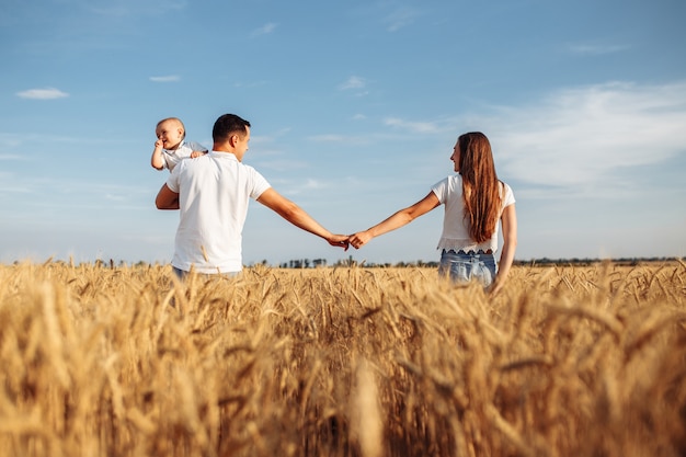 Coppia di innamorati con il loro bambino che cammina nel campo di grano