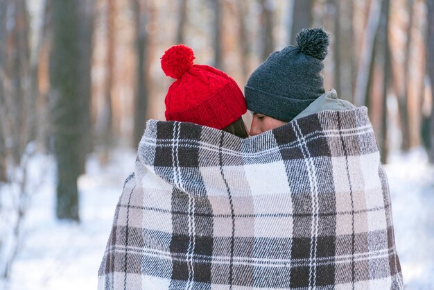 Coppia di innamorati in inverno nel parco sotto una calda coperta. Tenerezza, unità e amore.