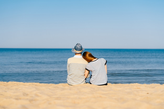 Coppia di innamorati seduti insieme sulla spiaggia