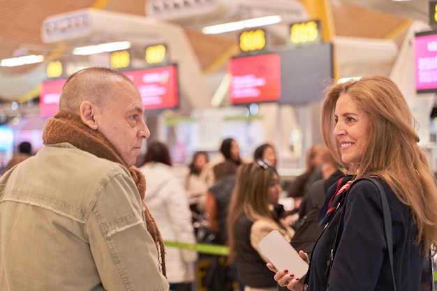 coppia di mezza età in fila all'aeroporto per fare il check-in e fare un viaggio nella coda del check-in