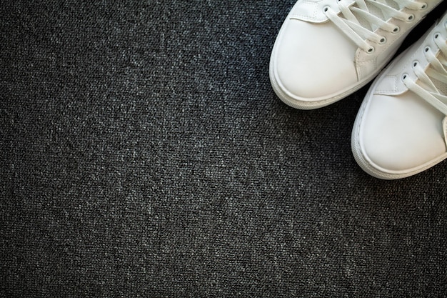 Coppia di nuove eleganti scarpe da ginnastica bianche sul pavimento di casa.