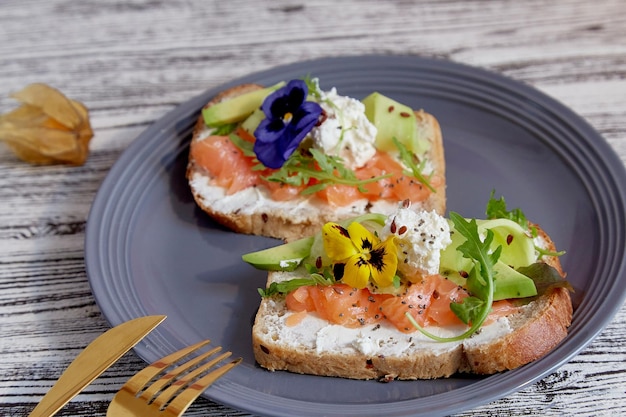 Coppia di panini con salmone avocado e fiori commestibili Sana colazione Dieta Pescetarian