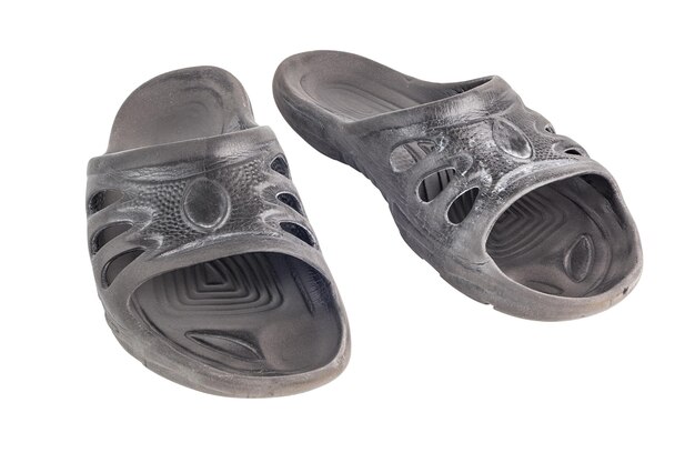 Coppia di pantofole in gomma morbida nera economiche usate con segni di usura da attrito isolati su sfondo bianco