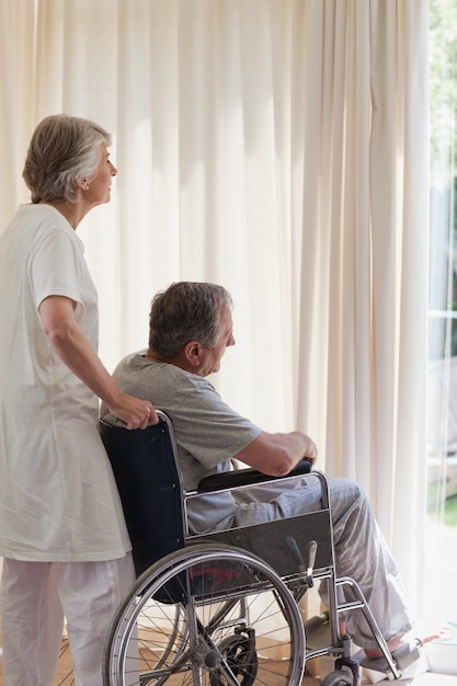 Coppia di pensionati guardando fuori dalla finestra