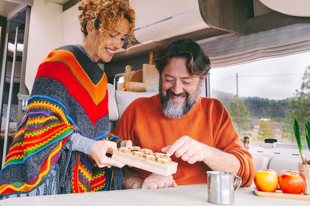 Coppia di persone si godono il tempo libero all'interno in un camper, un'auto da campeggio, un uomo e una donna adulti sorridono e si divertono durante le vacanze di viaggio o la vita in furgone, noleggiando un furgone o vivendo in stile vanlife, una casa alternativa moderna