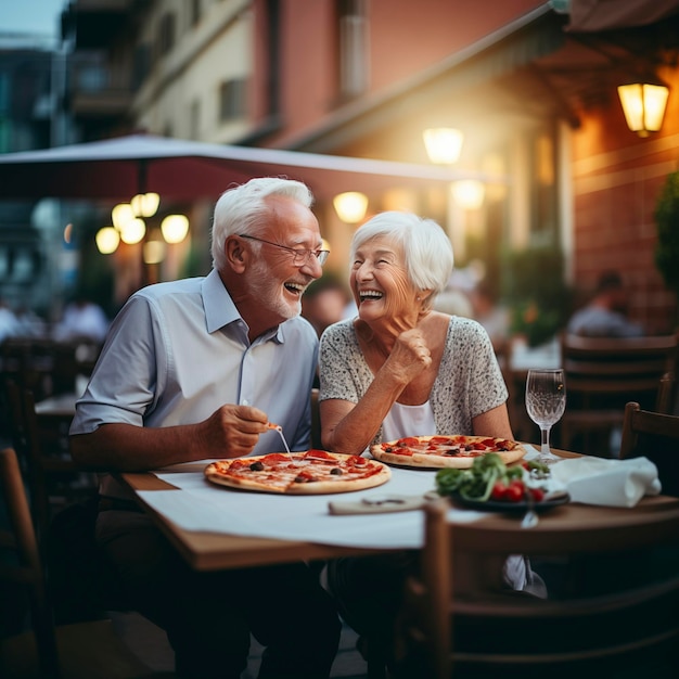 Coppia di signori anziani con i capelli bianchi sorridono mentre mangiano una pizza Festeggiamo l'anniversario in pizzeria seduti all'aperto Concetto di persone felici