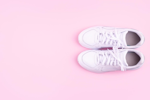 Coppia di sneakers bianche alla moda su sfondo rosa chiaro spazio piatto per il testo
