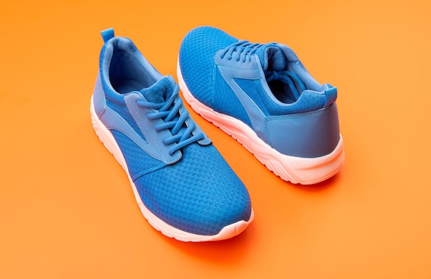 Coppia di sneakers blu sportive su sfondo arancione fitness