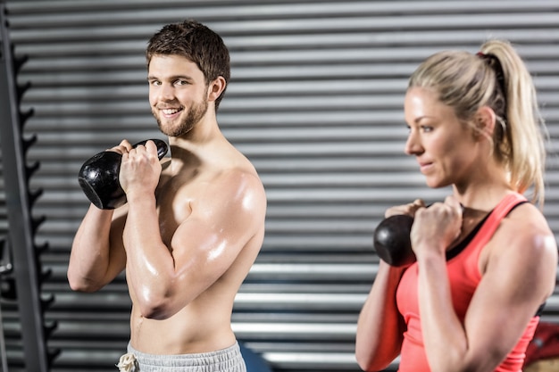 Coppia di sollevamento manubri insieme in palestra di crossfit