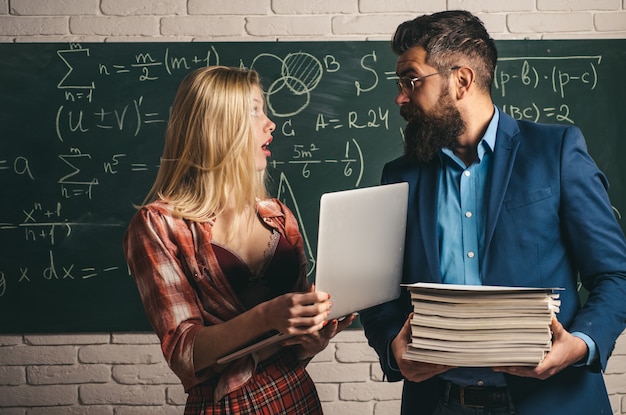 Coppia di studentessa abbastanza sexy che tiene mucchio di libri e insegnante di bell'uomo barbuto o