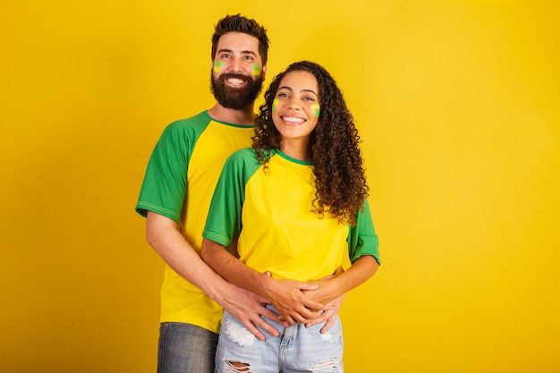 Coppia di tifosi di calcio brasiliani vestiti con i colori della nazione donna nera uomo caucasico insieme romantico