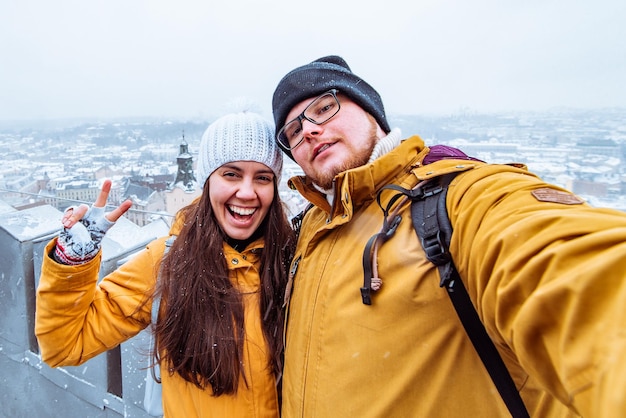 Coppia di turisti che prendono selfie con bella vista sulla città in inverno sullo sfondo