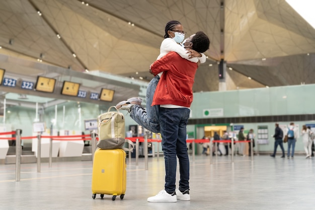 Coppia di turisti in maschere abbraccio in aeroporto