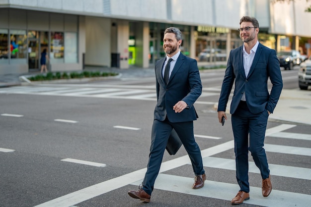 Coppia di uomini d'affari che attraversano il passaggio pedonale sulla strada della città americana all'aperto allegro Medio Oriente