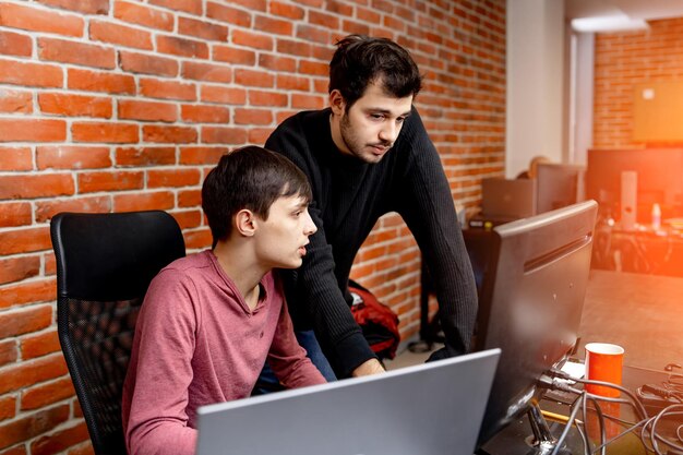 Coppia di uomini d'affari che lavorano con un nuovo progetto sul computer. Uomo bello che lavora in un ufficio moderno.