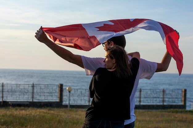 Coppia di uomini e donne che si abbracciano e stanno in piedi con la bandiera del Canada per celebrare la festa