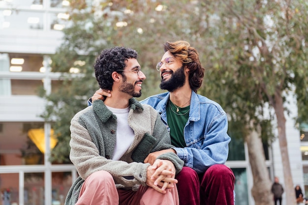 Coppia di uomini gay seduti in un parco sorridendo felice