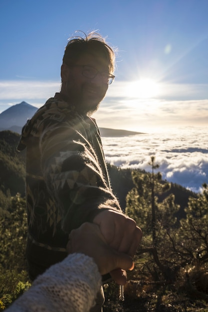 Coppia di viaggiatori avventurosi. La sagoma dell'uomo segue la donna che si tiene per mano facendo un'escursione sul paesaggio di montagna. Coppia che si gode un'escursione sulla cima della montagna