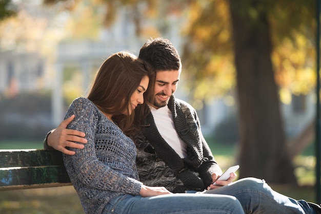 Coppia digitando sul telefono all'aperto nel parco