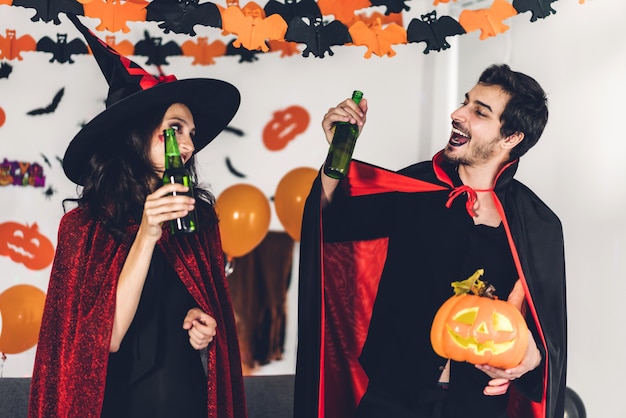 Coppia divertendosi tenendo le zucche e indossando costumi di halloween vestiti di carnevale