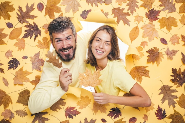 Coppia divertente si sta preparando per la vendita autunnale coppia romantica che indossa pullover su foglie d'autunno bac...