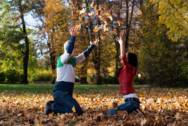 Coppia Divertirsi Con Foglie D'autunno In Giardino