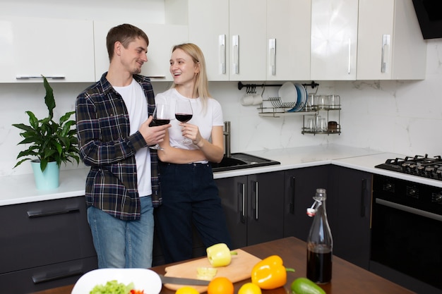 coppia divertirsi in cucina bevendo vino rosso