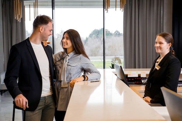 Coppia e receptionist al banco in hotel. Giovane coppia in viaggio d'affari facendo il check-in in hotel