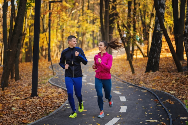 Coppia fare jogging e correre all'aperto nella natura autunnale