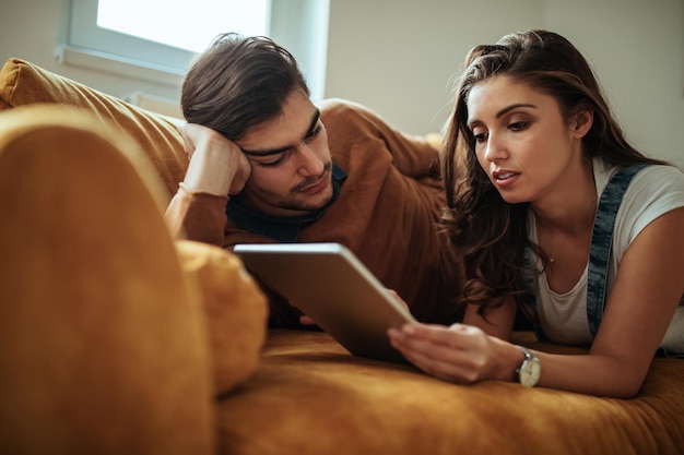 Coppia felice a casa usando la loro tavoletta digitale insieme