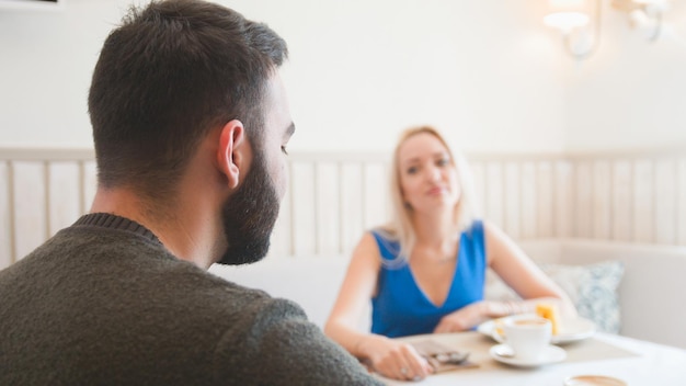 Coppia felice al caffè godendo i dessert e tenendosi per mano da vicino