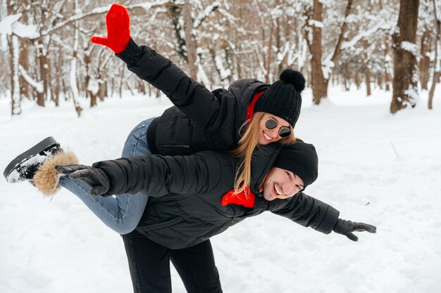 Coppia felice che abbraccia e sorride all'aperto nel parco innevato