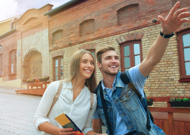 Coppia felice che cammina all'aperto per visitare la città e tiene in mano una mappa.