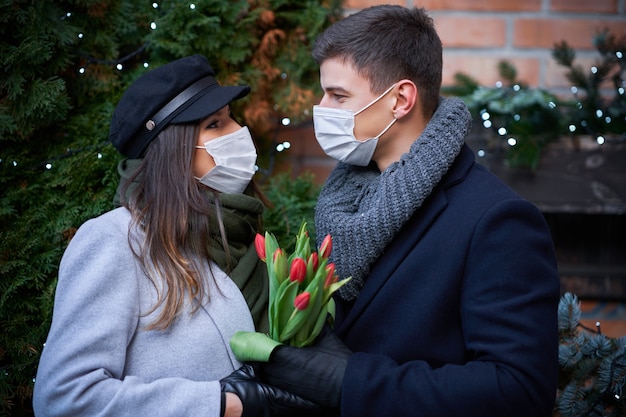 Coppia felice che celebra San Valentino in maschera durante la pandemia di covid-19 in città