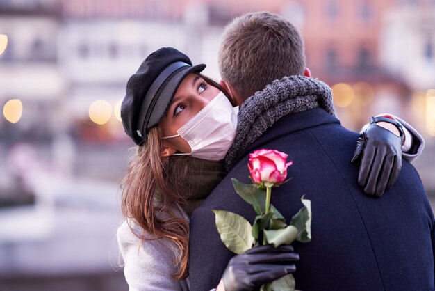 Coppia felice che celebra San Valentino in maschera durante la pandemia di covid-19 in città