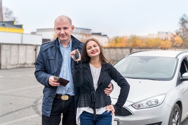 Coppia felice che compra una nuova auto in posa all'aperto