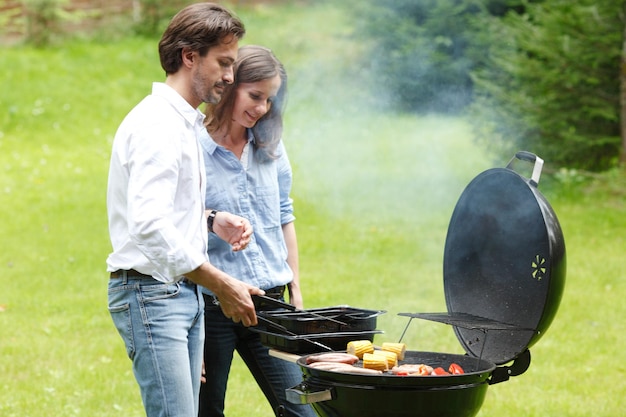 Coppia felice che cucina cibo sul barbecue