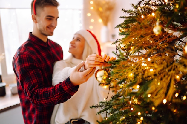 Coppia felice che decora l'albero di Natale a casa Uomo e donna sorridenti che festeggiano insieme il Natale