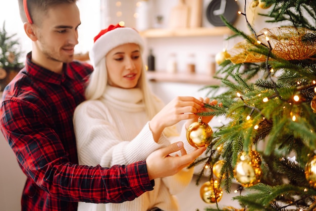 Coppia felice che decora l'albero di Natale a casa Uomo e donna sorridenti che festeggiano insieme il Natale